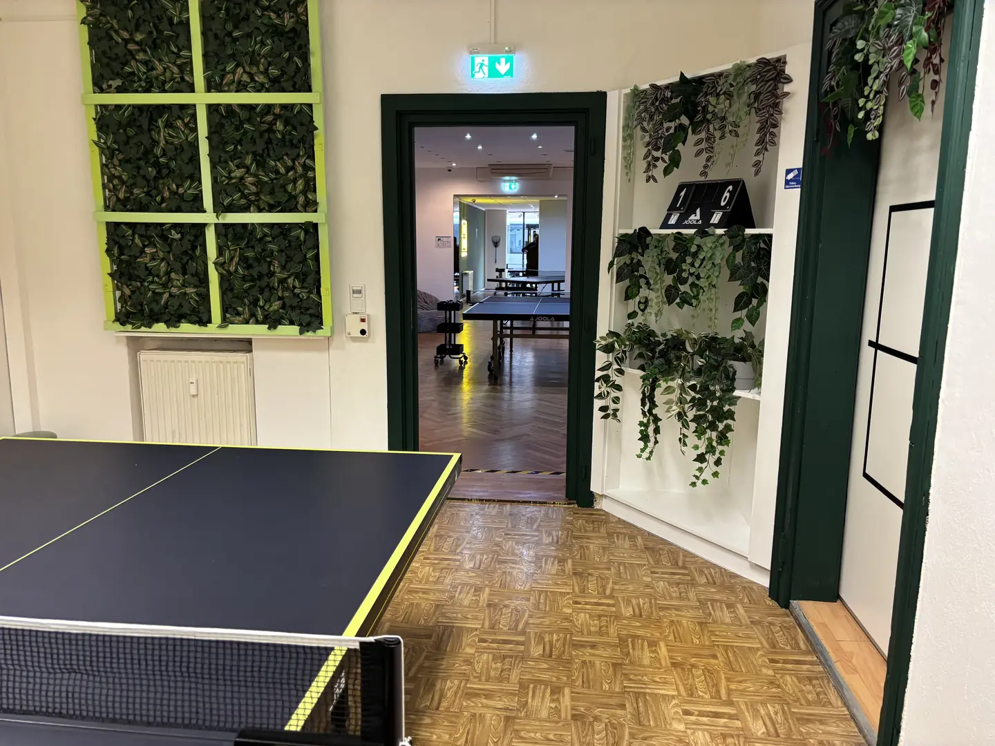 Grüner Durchgang mit Pflanzendekor und Blick in den nächsten Spielraum