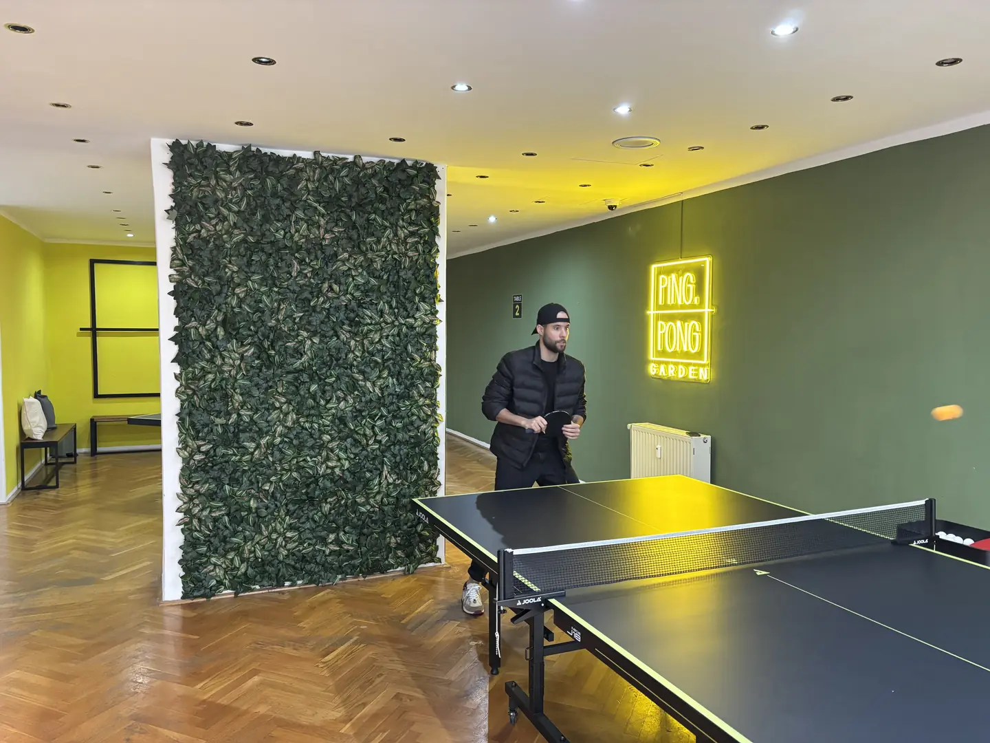Mooswand neben der Tischtennisplatte, im Hintergrund das Neonschild