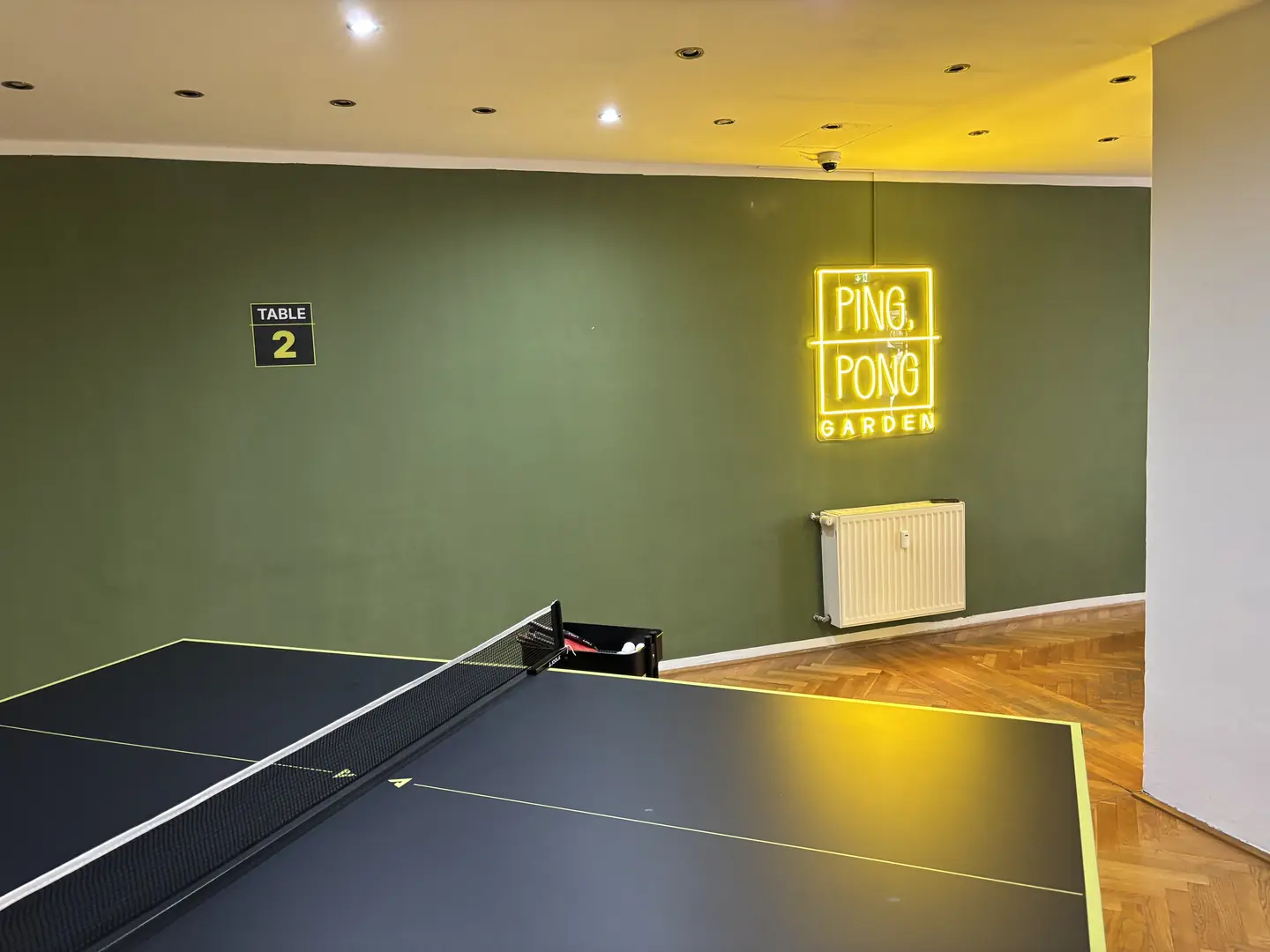 Tisch 2 vor der grünen Wand mit leuchtendem Ping-Pong-Garden-Neonschild