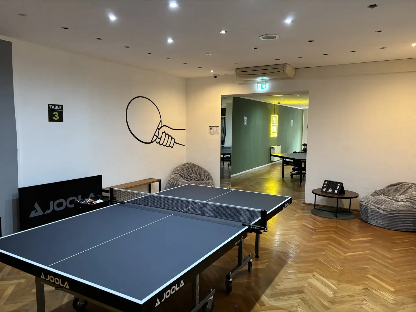 Tischtennisplatte an Tisch 3 vor der Wandgrafik mit Schläger und Ball